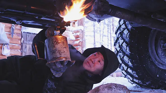 A truck driver uses a small flamethrower to thaw the drive shaft of his truck. This picture was taken in the tundra, between Oymyakon and Yakutsk.